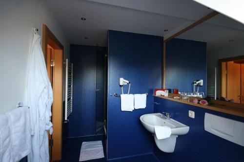 Baño azul con lavabo y aseo en Landhaus Lebert Restaurant, en Windelsbach
