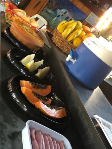 a table topped with plates of meats and fruit at Pousada Miramar in Marataizes