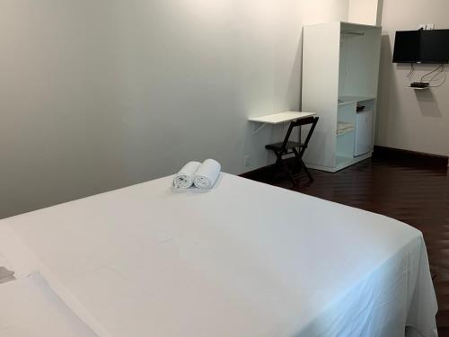 a white bed with a pair of shoes on it at SAMIR HOTEL COMFORT in Porto Velho