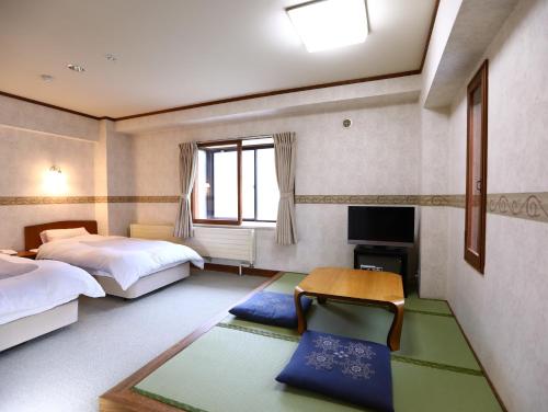 a room with two beds and a table and a tv at New Yokote in Yamanouchi