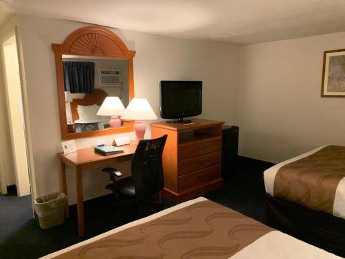 a hotel room with a desk with a television and a bed at America's Best Value Inn Sandpoint in Sandpoint