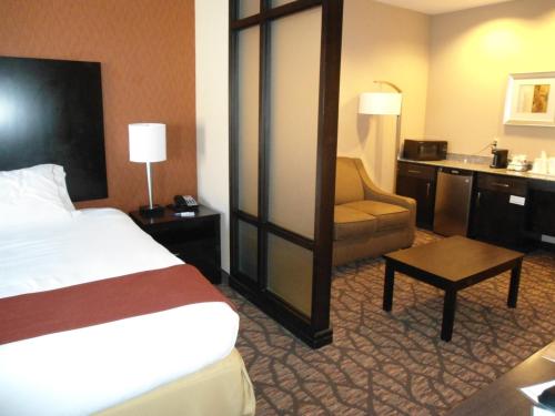 a hotel room with a bed and a chair at Holiday Inn Express and Suites Alpine by IHG in Alpine