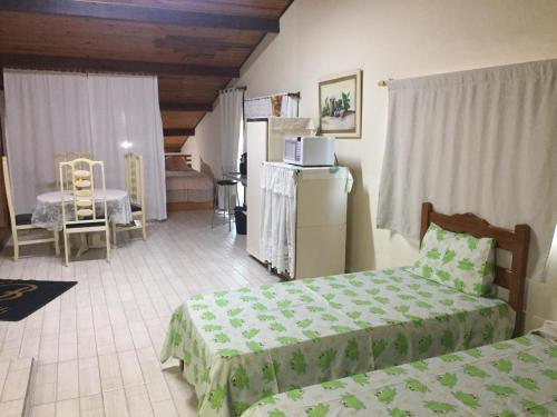 1 dormitorio con 2 camas y cocina con nevera. en Sótão Studio Relax, en Peruíbe