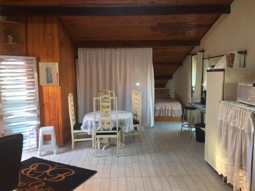 Habitación con mesa, sillas y nevera. en Sótão Studio Relax, en Peruíbe