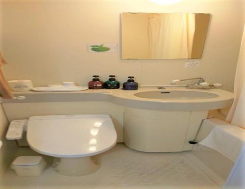 a bathroom with a white toilet and a sink at Amami Port Tower Hotel in Amami