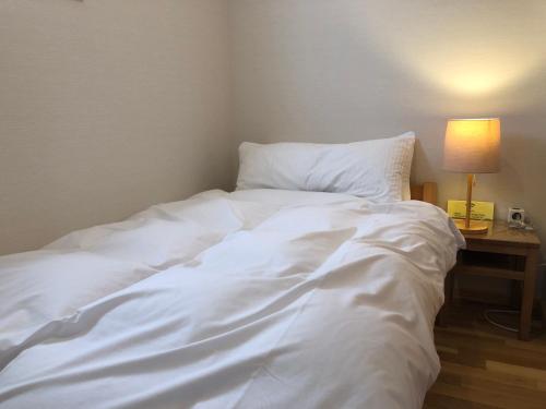 a white bed in a room with a table with a lamp at Hotel Resort Inn Niseko in Niseko