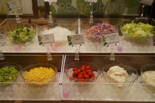 東京にあるスマイルホテル東京日本橋のさまざまな種類の食べ物が入ったボウルが並んだ陳列ケース