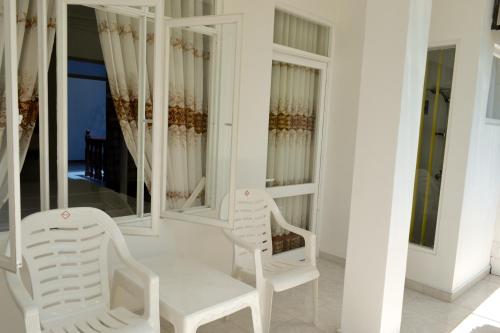 2 chaises blanches et une table dans une chambre avec miroirs dans l'établissement Di Sicuro Tourist Inn, à Hikkaduwa