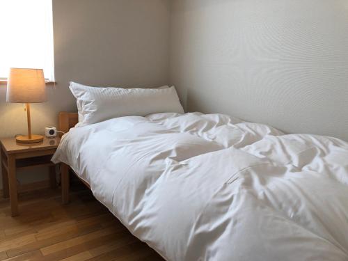 a white bed in a room with a table with a lamp at Hotel Resort Inn Niseko in Niseko