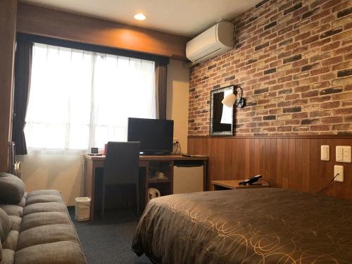 a hotel room with a bed and a desk and a brick wall at Global Resort ONO de LUNE in Hatsukaichi