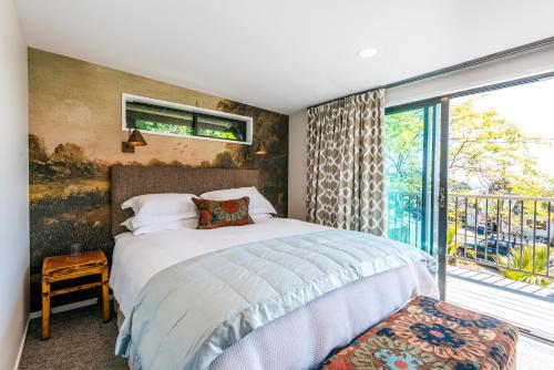 a bedroom with a bed and a large window at Moana on Waikare - You've Got It Maid in Oneroa