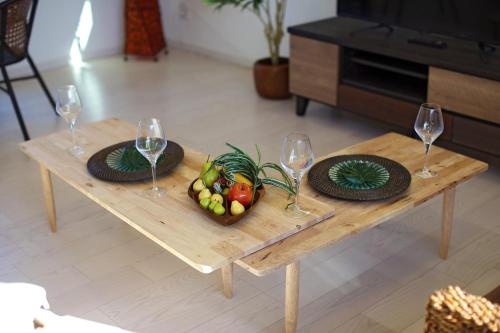 a wooden table with two wine glasses and a bowl of fruit at Irie House Fuchaku in Onna