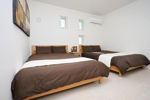 two beds in a room with white walls at Irie House Fuchaku in Onna