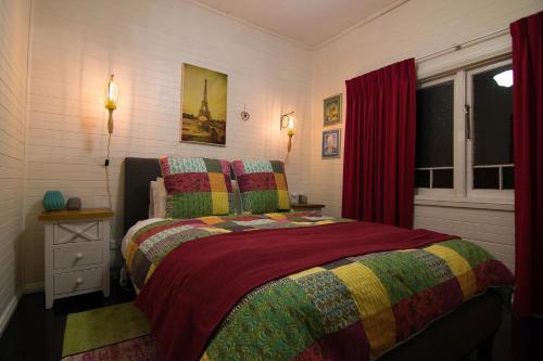 a bedroom with a bed with a colorful blanket at Piccolo in Leura