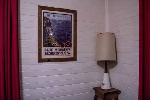 a picture of a poster on a wall with a lamp at Piccolo in Leura