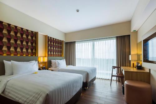 a hotel room with two beds and a desk at Best Western Kamala Jimbaran in Jimbaran