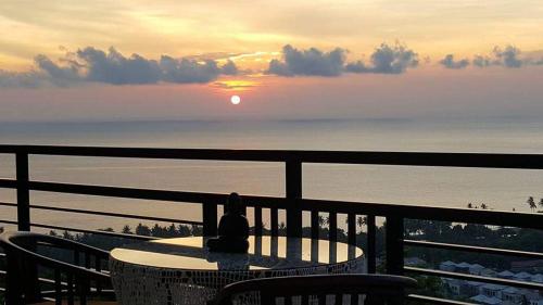 a person sitting at a table on a balcony watching the sunset at Villa Aryaguna in Senggigi 