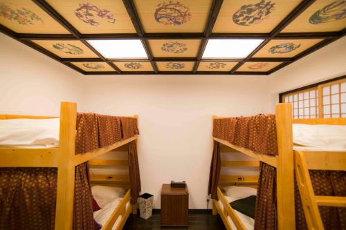 a room with three bunk beds and a ceiling at Shinjuku Miyabi Residence in Tokyo