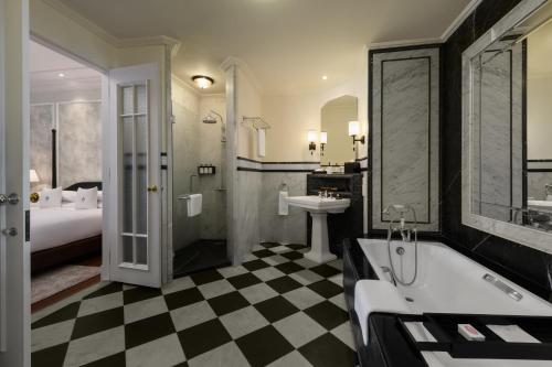 a bathroom with a black and white checkered floor at Eastern & Oriental Hotel in George Town