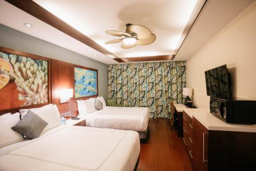 Surfrider Resort Hotel في سايبان: غرفه فندقيه سريرين وتلفزيون