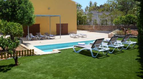 a group of lawn chairs and a swimming pool at Ca'n Pedro in Sa Coma