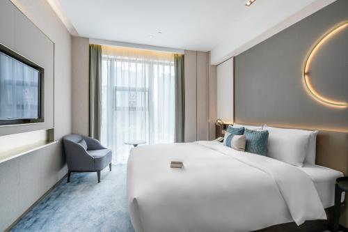 una camera d'albergo con un grande letto bianco e una sedia di Anban Hotel Shenzhen a Shenzhen