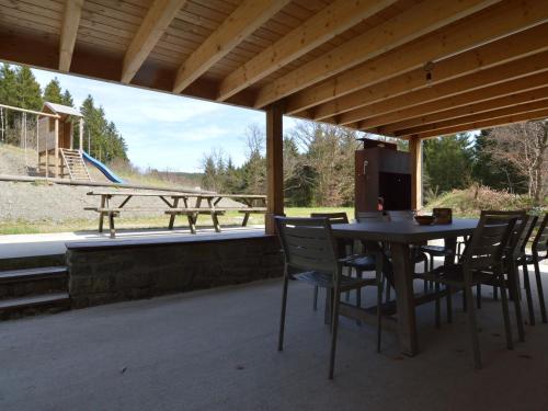 um alpendre com mesa e cadeiras e um parque infantil em Holiday home in the middle of nature with sauna em Longfaye