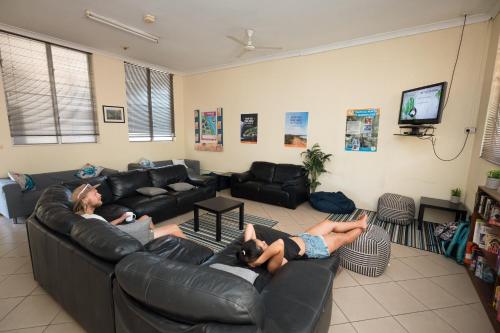 two people laying on leather couches in a living room at Rockhampton Backpackers in Rockhampton