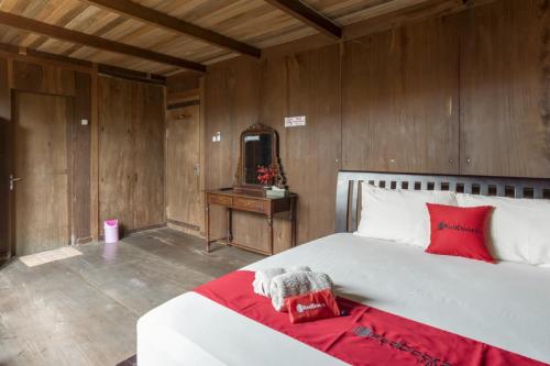 a bedroom with a white bed with red pillows and a mirror at RedDoorz at Omah Kayu Homestay Yogyakarta in Yogyakarta