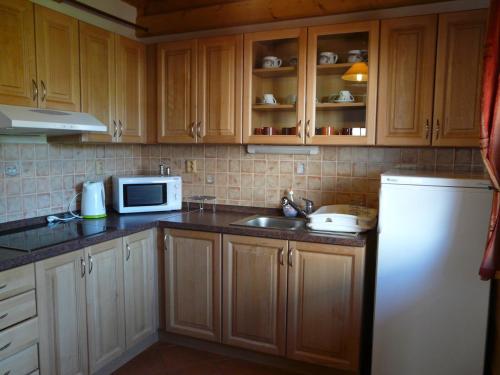 a kitchen with wooden cabinets and a sink and a microwave at Rekreačné chalupy in Liptovský Trnovec