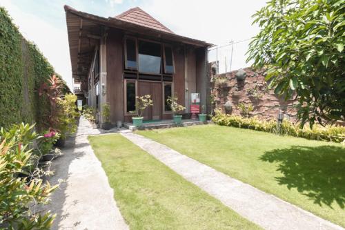 a house with a lawn in front of it at RedDoorz at Omah Kayu Homestay Yogyakarta in Yogyakarta
