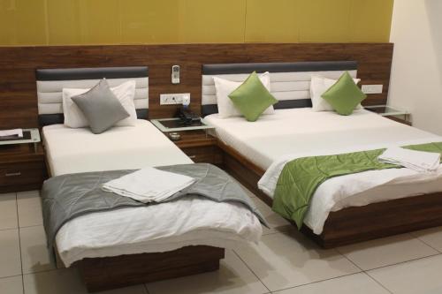 a bedroom with two beds with green pillows at HOTEL SATKAR CHHATRAL in Kalol
