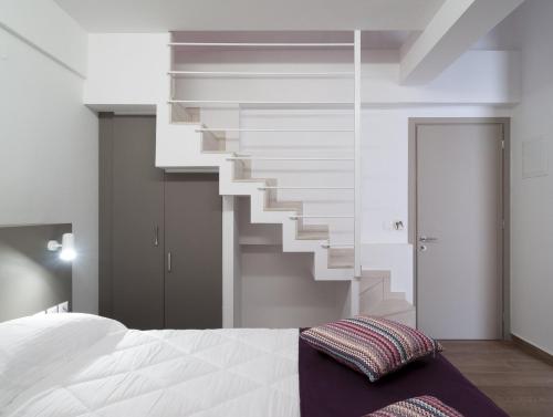 Un dormitorio con una cama blanca y una escalera en Olympos Suites Apartments, en Leptokarya
