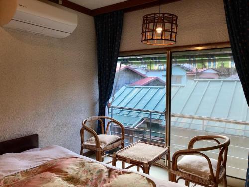 een slaapkamer met een bed en 2 stoelen en een raam bij Tsukinoya in Hakone