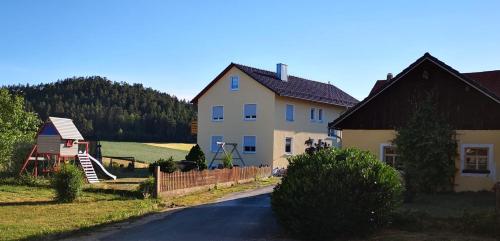 uma casa numa estrada ao lado de uma casa em Ferienwohnung Hutzler em Pottenstein