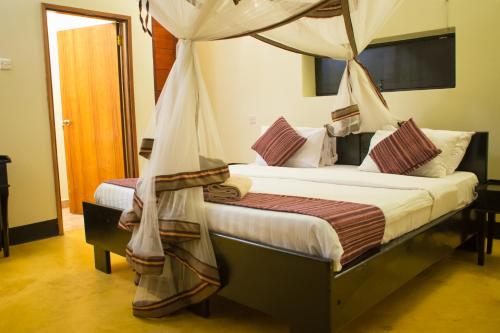 a bedroom with two beds with a canopy at Fort Murchison Lodge by NATURE LODGES LTD in Pakwach East