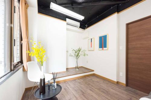 a room with a chair and a table with flowers at TORA HOTEL Tokyo-Rikugienn 寅ホテル 六義園 A in Tokyo