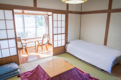 Habitación pequeña con cama y mesa en Ryokan Fuji Heights en Fujikawaguchiko