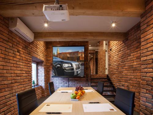 a dining room with a table and a tv on a brick wall at Hotel Betmanowska Main Square Residence Adults Only in Kraków
