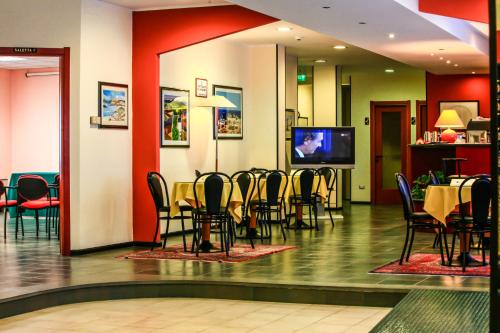a dining room with tables and chairs and a tv at Hotel Quadrifoglio in Cagliari