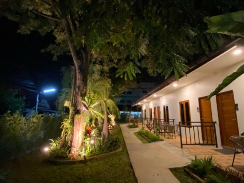 a patio at night with a tree and lights at The Cozy Hotel in Phetchaburi