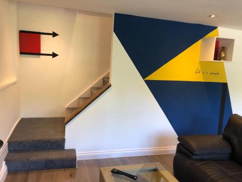 a living room with a staircase and a painting on the wall at Old Fleece Apartments in Stroud