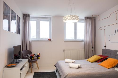 a bedroom with a bed and a desk and windows at Willow Pillow Nowowiejska in Warsaw