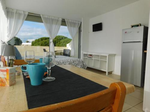 een keuken en een woonkamer met een tafel met wijnglazen bij studio 38 climatisé balcon vue mer in Le Grau-du-Roi