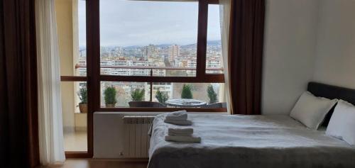 a bedroom with a bed and a large window at Студио Тони в модерна сграда с фитнес в централна Варна in Varna City