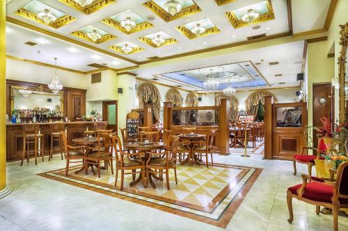 a restaurant with wooden tables and chairs and a bar at Imperial Palace Classical Hotel Thessaloniki in Thessaloniki