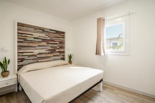 a white bedroom with a bed and a window at Onda Blu Resort in Manerba del Garda