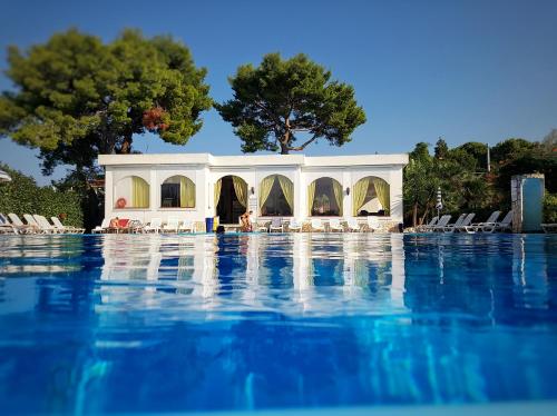 a swimming pool with chairs and a building at Villaggio Alba Chiara in Vieste