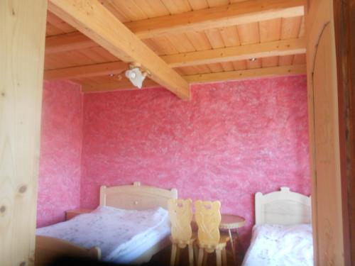 - une chambre avec 2 lits et un mur rose dans l'établissement Gospodarstwo Karolina, à Huba