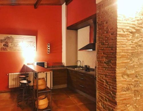 a kitchen with red walls and a counter with a table at FINCA LAS DEHESILLAS in Monesterio